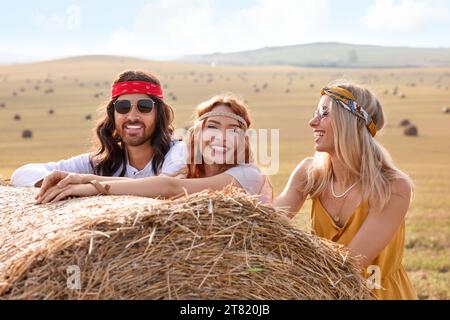 Amici hippie felici vicino alla balla di fieno nel campo Foto Stock