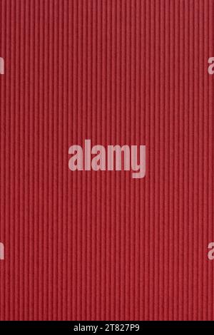 primo piano della texture della superficie in carta artigianale di colore rosso caldo, cartone ondulato decorativo e a righe per biglietti di auguri per natale, capodanno o valentini Foto Stock