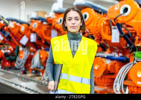 Ritratto di un ingegnere donna di una fabbrica di produzione di bracci robotici che guarda la fotocamera Foto Stock