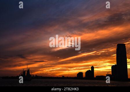 Un tramonto incandescente su Jersey City e il fiume Hudson - Vista dal Battery Park a Manhattan, New York City Foto Stock