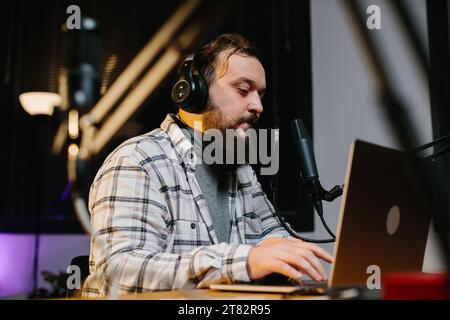 Un blogger online parla in un microfono durante uno streaming. Presentatore radiofonico in studio durante la trasmissione. Foto Stock