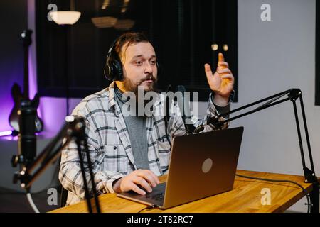 Un blogger online parla in un microfono durante uno streaming. Presentatore radiofonico in studio durante la trasmissione. Foto Stock