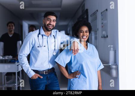 Ritratto di medici maschi e femmine felici e diversificati in piedi nel corridoio dell'ospedale Foto Stock