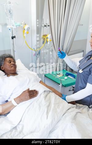 Medico femminile diversificato e paziente anziano in camera d'ospedale Foto Stock
