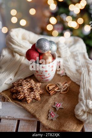 Tazza di Capodanno con giocattoli di Capodanno e pan di zenzero. Il concetto di vacanze invernali. Atmosfera intima e magica nella casa. Foto Stock