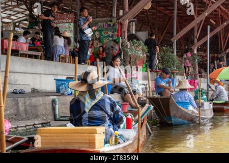 Vari beni, come cibo o bevande tailandesi, sono offerti in vendita su un mercato galleggiante originale Samut Sakhon Thailandia Asia Foto Stock