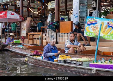 Vari beni, come cibo o bevande tailandesi, sono offerti in vendita su un mercato galleggiante originale Samut Sakhon Thailandia Asia Foto Stock