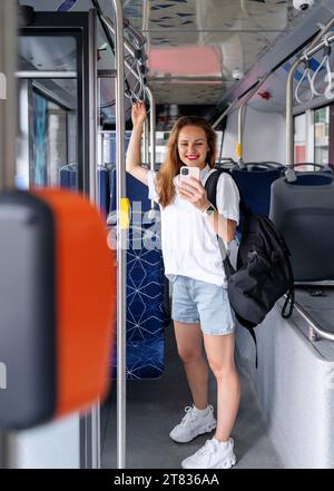 Stile di vita urbano, le donne passeggeri utilizzano il proprio telefono cellulare mentre si trovano all'interno del filobus. Persone e mezzi pubblici in città. Foto Stock