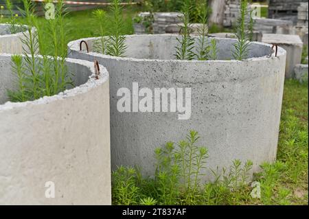 anelli in cemento abbandonati o dimenticati per la costruzione di pozzi rotondi di drenaggio Foto Stock