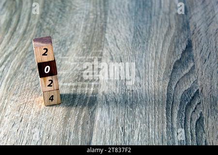 Cubi di legno con 2024 e felice anno nuovo su sfondo di legno, striscione con spazio per la copia del testo, modello di biglietto di auguri per l'anno nuovo Foto Stock