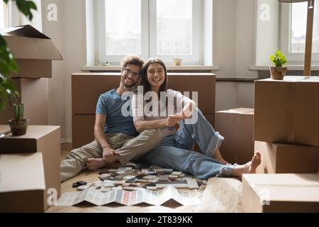 Ritratto della famiglia di proprietari di casa seduto sul pavimento guardando la fotocamera Foto Stock