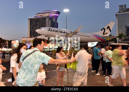 Gli acquirenti fuori dal Terminal 21 Shopping Mall, Pattaya, Thailandia, Sud Est Asiatico; alcuni scattano foto di un aereo con testo del Terminal 21 con un albero di Natale, scattato il 18 novembre 2023. Foto Stock