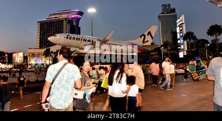 Gli acquirenti fuori dal Terminal 21 Shopping Mall, Pattaya, Thailandia, Sud Est Asiatico; alcuni scattano foto di un aereo con testo del Terminal 21 con un albero di Natale, scattato il 18 novembre 2023. Foto Stock