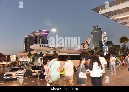 Gli acquirenti fuori dal Terminal 21 Shopping Mall, Pattaya, Thailandia, Sud Est Asiatico; alcuni scattano foto di un aereo con testo del Terminal 21 con un albero di Natale, scattato il 18 novembre 2023. Foto Stock