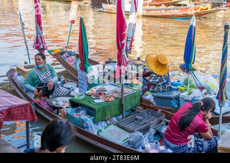 Vari beni, come cibo o bevande tailandesi, sono offerti in vendita su un mercato galleggiante originale Samut Sakhon Thailandia Asia Foto Stock