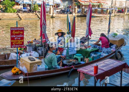 Vari beni, come cibo o bevande tailandesi, sono offerti in vendita su un mercato galleggiante originale Samut Sakhon Thailandia Asia Foto Stock