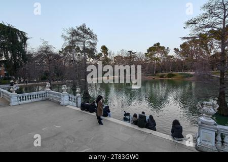 MADRID SPAGNA - 16 novembre 2023: Giovani seduti al tramonto sui gradini di un angolo del Parco del Retiro a Madrid che guardano il tranquillo lago. Foto Stock