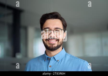 Un giovane uomo d'affari latino sorridente che indossa occhiali, ritratto alla testa. Foto Stock