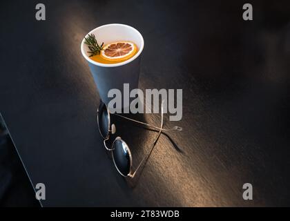 Bicchieri retrò con caffè arancione in tazza di carta su un tavolo di legno Foto Stock