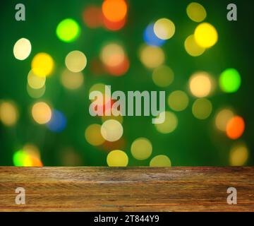 modello o sfondo natalizio, con luci natalizie multicolore e palline bokeh e tavolo vuoto in legno. Primo piano con spazio libero per gli oggetti AN Foto Stock