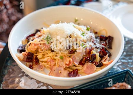 Mescolare il peperoncino secco fritto, la pancetta e le erbe nel piatto bianco del ristorante italiano Foto Stock