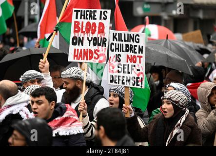 Duesseldorf, Germania. 18 novembre 2023. I manifestanti marciano per la città cantando "libertà per la Palestina” per protestare contro la guerra nella Striscia di Gaza - alcuni portano cartelli con la scritta "le mani sono sporche di sangue” e "uccidere bambini non è autodifesa!”. Crediti: Roberto Pfeil/dpa/Alamy Live News Foto Stock