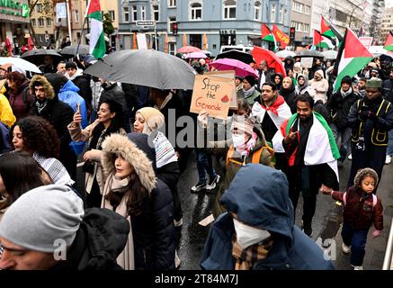 Duesseldorf, Germania. 18 novembre 2023. I manifestanti - tra cui una donna con il cartello "Stop the Genocide” - marciano attraverso la città cantando "libertà per la Palestina” per protestare contro la guerra nella Striscia di Gaza. Crediti: Roberto Pfeil/dpa/Alamy Live News Foto Stock