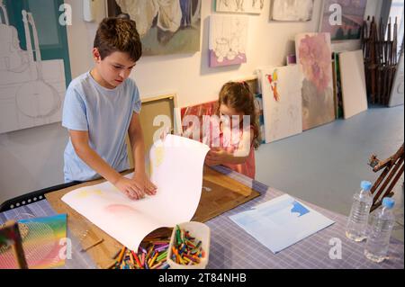 Ritratto autentico di due adorabili bambini, un preadolescente e una bambina, fratello e sorella che disegnano, che si godono un hobby creativo durante una lezione d'arte in una W. Foto Stock