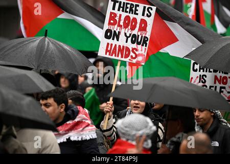 Duesseldorf, Germania. 18 novembre 2023. I manifestanti marciano attraverso la città cantando "libertà per la Palestina” per protestare contro la guerra nella Striscia di Gaza - un partecipante porta con sé un cartello con la scritta "le mani sono sporche di sangue”. Crediti: Roberto Pfeil/dpa/Alamy Live News Foto Stock