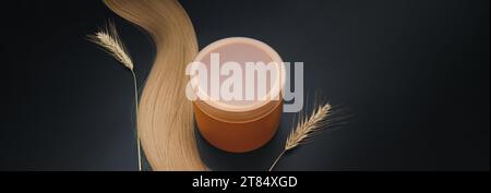 Capelli lunghi biondi con vaso panna e ciuffi di grano maturo. Capelli sani. Strumenti per capelli, bellezza e concetto di parrucchiere. Foto Stock