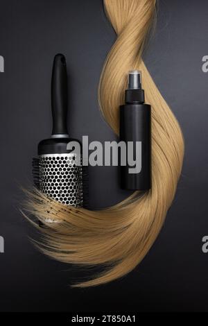 Capelli lunghi biondi, spazzola rotonda per acconciare i capelli con spray per la cura dei capelli. Capelli sani. Accessori per il taglio di capelli con spazio per la copia. Trattamento di riparazione delle doppie punte Foto Stock