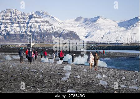 I turisti che camminano lungo la riva di Breiðamerkursandur, o Diamond Beach, vicino alla laguna di Jokulsarlon, con iceberg lavati sulla costa, l'Islanda Foto Stock