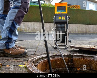 Un'azienda di pulizia degli scarichi controlla uno scarico ostruito con una telecamera prima di lavarlo fuori Foto Stock