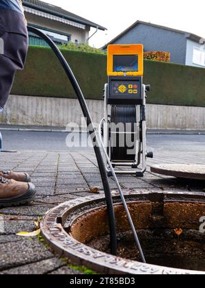 Un'azienda di pulizia degli scarichi controlla uno scarico ostruito con una telecamera prima di lavarlo fuori Foto Stock