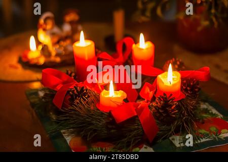 Corona d'avvento fatta di rami di pino con quattro candele brucianti Foto Stock