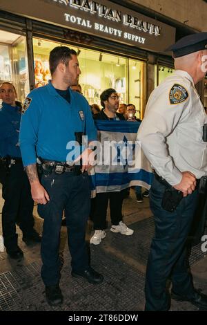 Manhattan, USA. 17 novembre 2023. La persona che detiene la bandiera israeliana è circondata da agenti di polizia mentre si trovano di fronte a migliaia di manifestanti che sostengono la Palestina a Midtown, Manhattan, NY, venerdì 17 novembre 2023. Questa è una delle proteste quasi quotidiane a New York e in tutto il mondo che chiedono un cessate il fuoco a Gaza dopo sei settimane di guerra Israele-Hamas. (Foto di Cristina Matuozzi/ Credit: SIPA USA/Alamy Live News Foto Stock