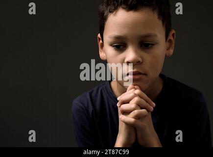 Ragazzo che prega Dio con le mani tenute insieme alla gente calza la foto di scorta Foto Stock