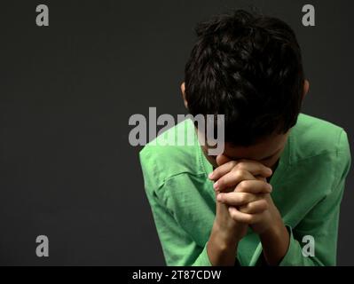 Ragazzo che prega Dio con le mani tenute insieme alla gente calza la foto di scorta Foto Stock