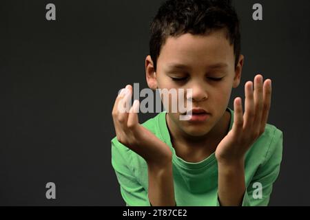 Ragazzo che prega Dio con le mani tenute insieme alla gente calza la foto di scorta Foto Stock