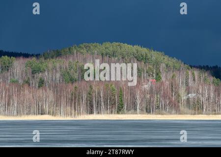 Il ghiaccio tenero e sottile sta per rompersi su un lago nella Finlandia occidentale all'inizio di aprile del 2011, con le sue spettacolari nuvole scure che si muovono in una collina ricoperta di spirito Foto Stock