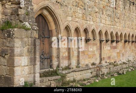 Antica porta ad arco in legno e archi sul lato di un'abbazia Foto Stock