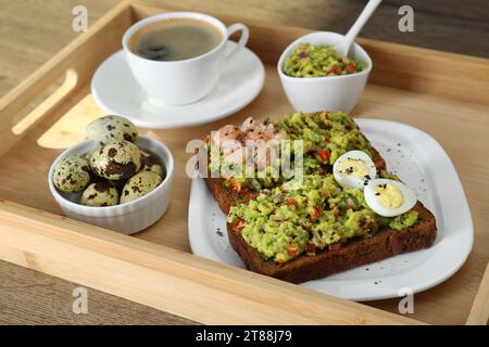 Fette di pane con guacamole, uova, gamberi e caffè su un tavolo di legno Foto Stock