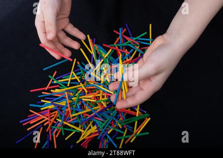 Bambino che gioca con bastoni di legno colorati per la creatività su sfondo bianco Foto Stock