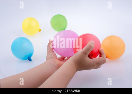 Mano che tiene un palloncino colorato con palloncini colorati sullo sfondo bianco Foto Stock