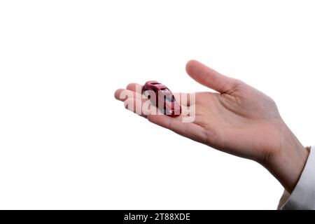 Bambino la mano che regge un auto rossa su uno sfondo bianco Foto Stock