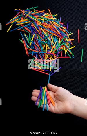 Bambino che gioca con bastoni di legno colorati per la creatività su sfondo bianco Foto Stock