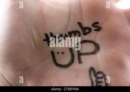 Pollici su scritto sul palmo della mano su uno sfondo bianco Foto Stock