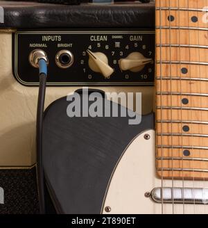 Chitarra elettrica in bianco e nero con amplificatore a tubo e cavo. Foto Stock