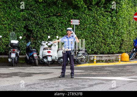 Una poliziotta in uniforme dirige il traffico ad un incrocio a Bellagio, Lombardia, Italia. Foto Stock