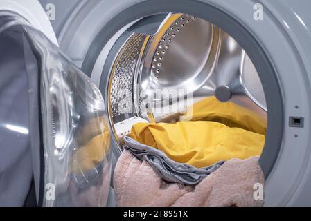 Il tamburo (serbatoio) della lavatrice anteriore con il bucato interno. Foto Stock